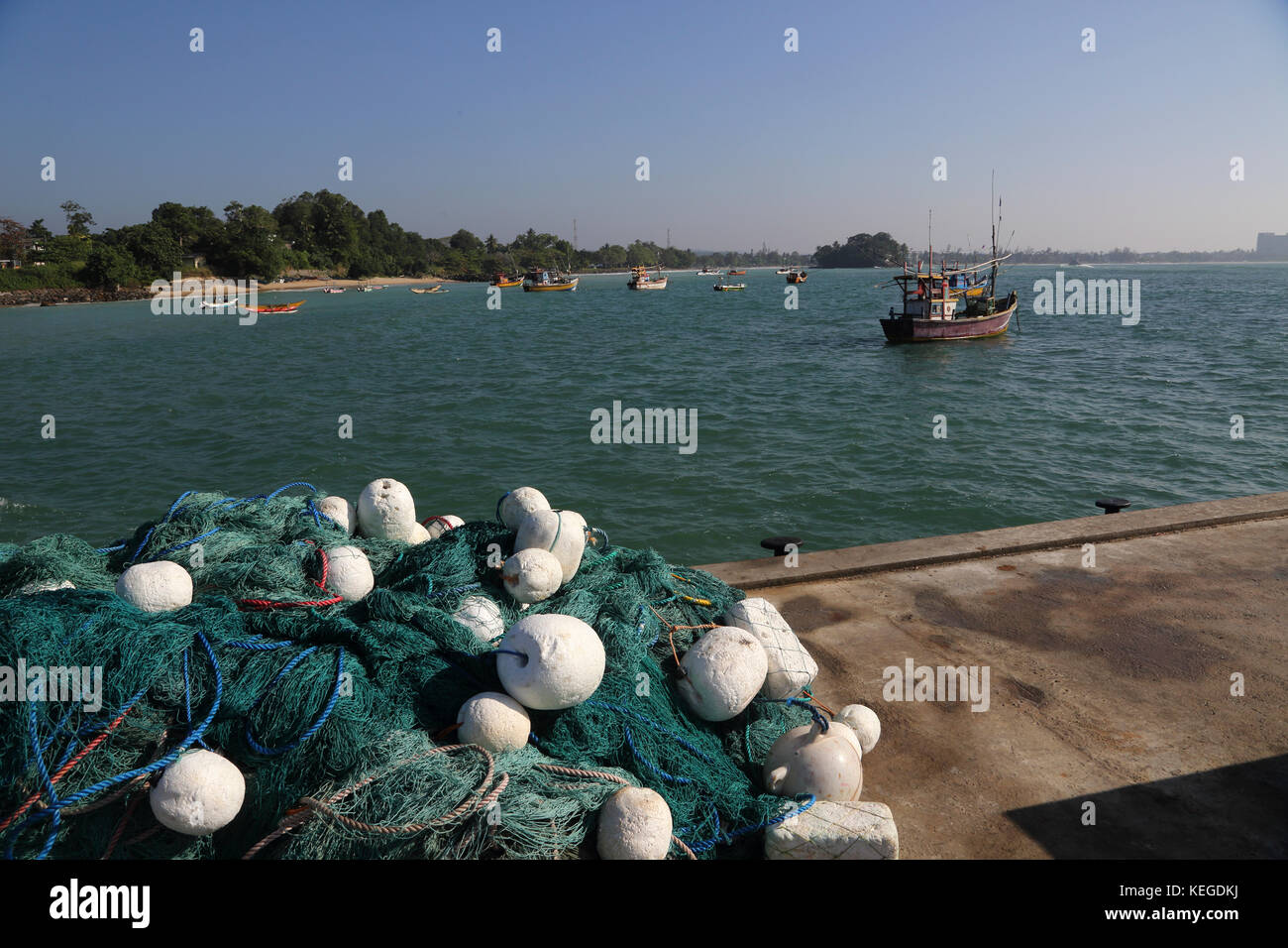 Una foto vertical de redes de pesca en el muelle del puerto y barcos de  pesca atracados en el fondo Fotografía de stock - Alamy