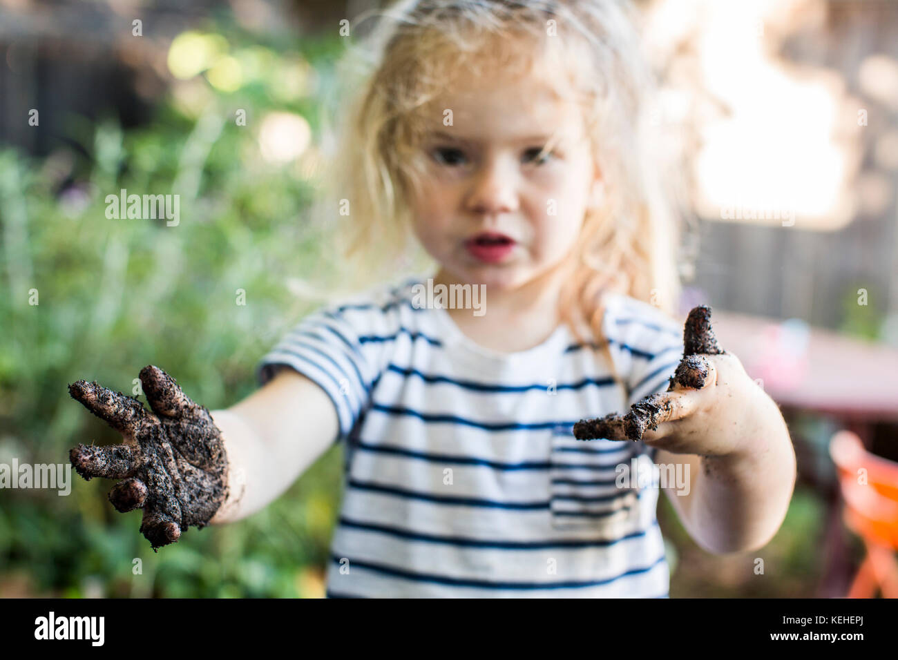 Chica caucásica con manos fangosas en el jardín Foto de stock