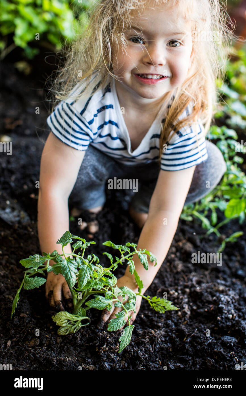 Chica caucásica posando con planta en el jardín Foto de stock