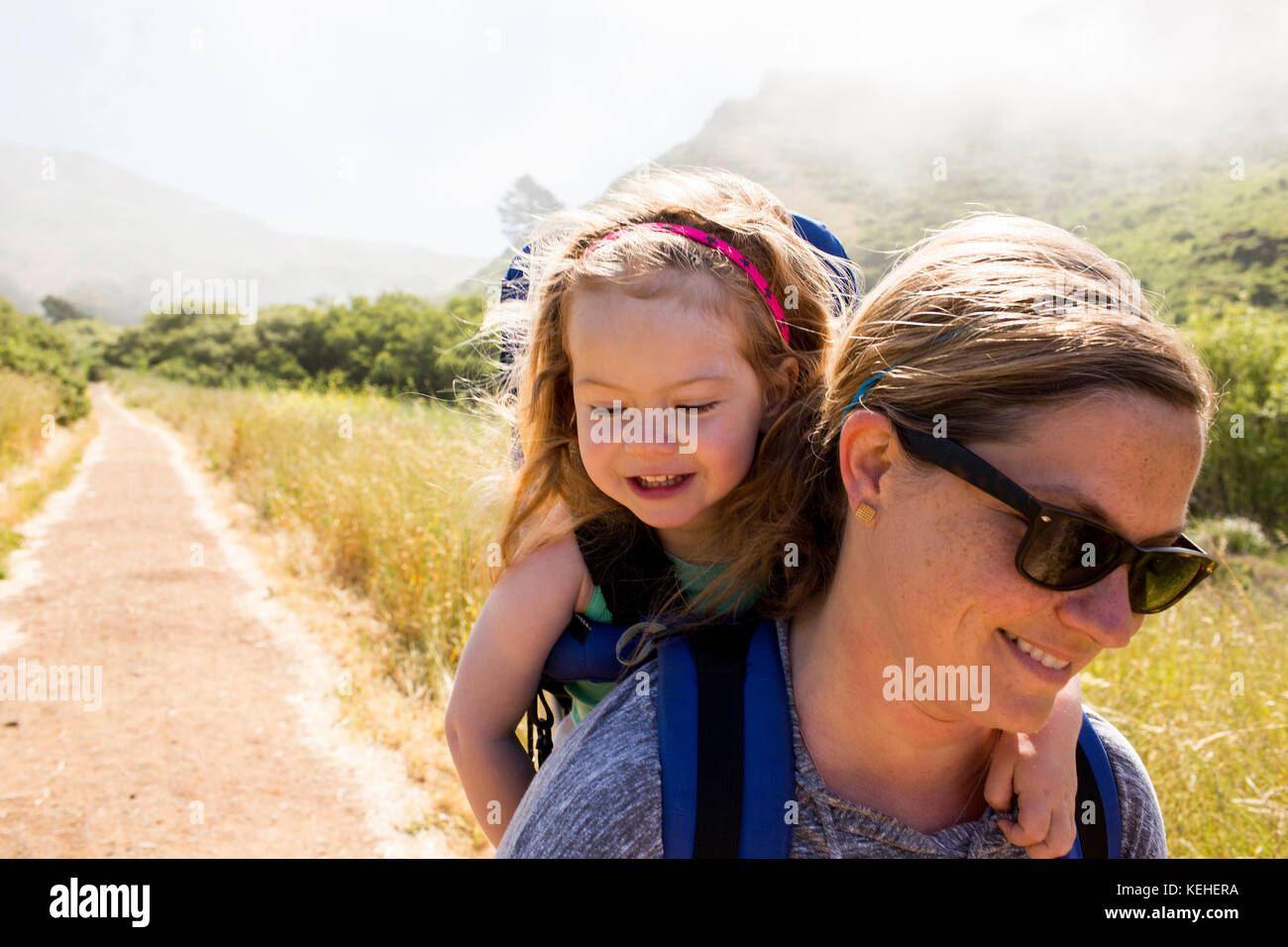 Madre caucásica llevando a su hija mientras se hace senderismo Foto de stock