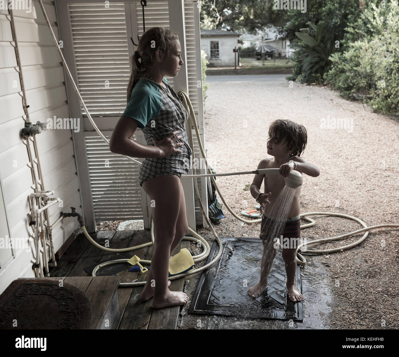 Frustrada chica caucásica viendo a su hermano usando la ducha al aire libre Foto de stock