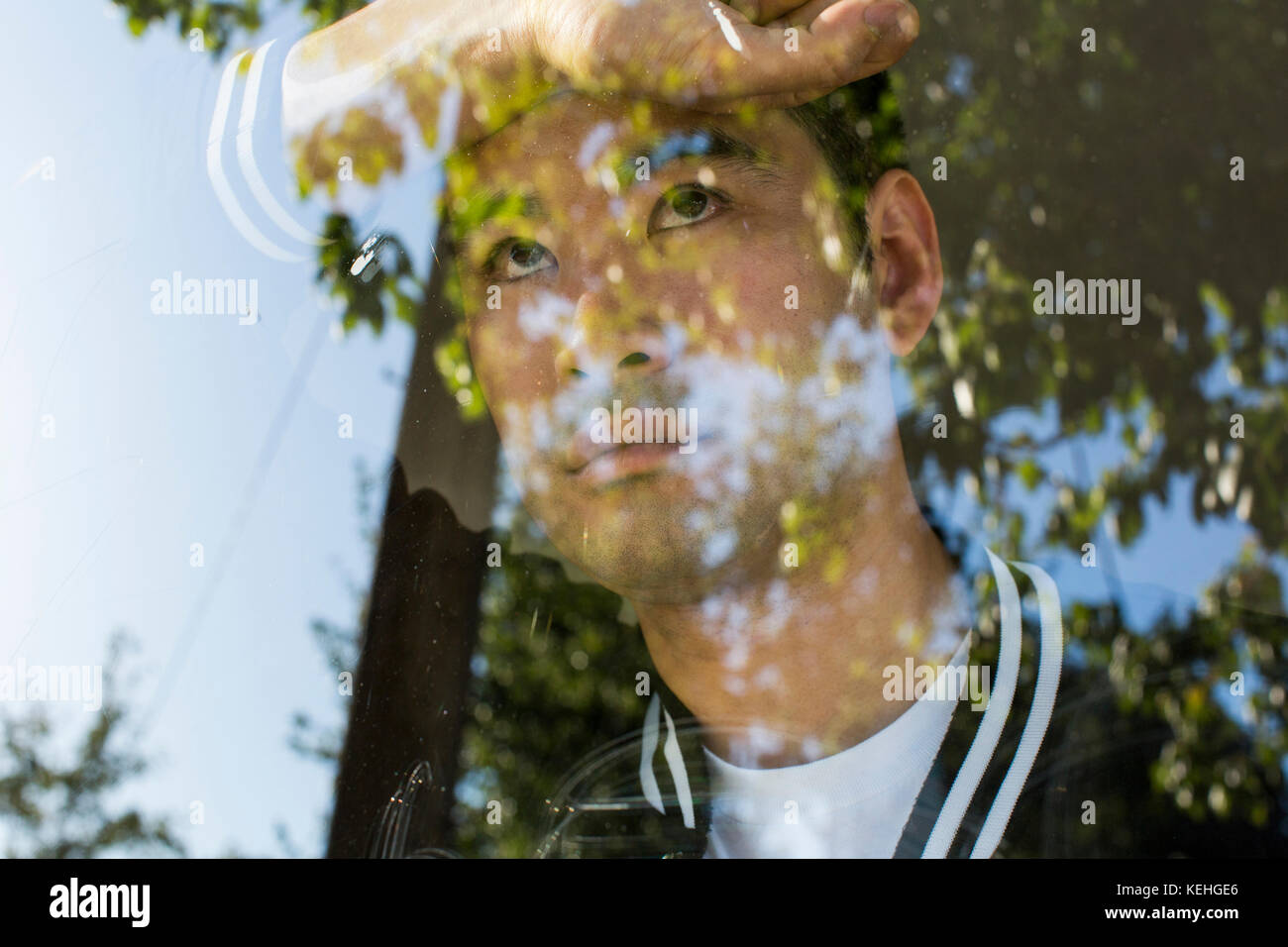 Un hombre chino serio apoyado en la ventana Foto de stock