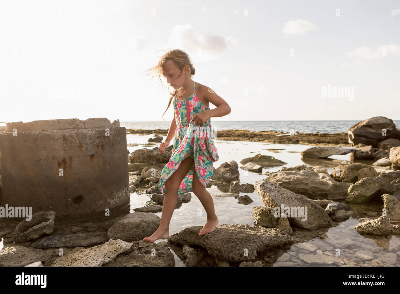 Chica caucásica caminando sobre las rocas en la playa Foto de stock