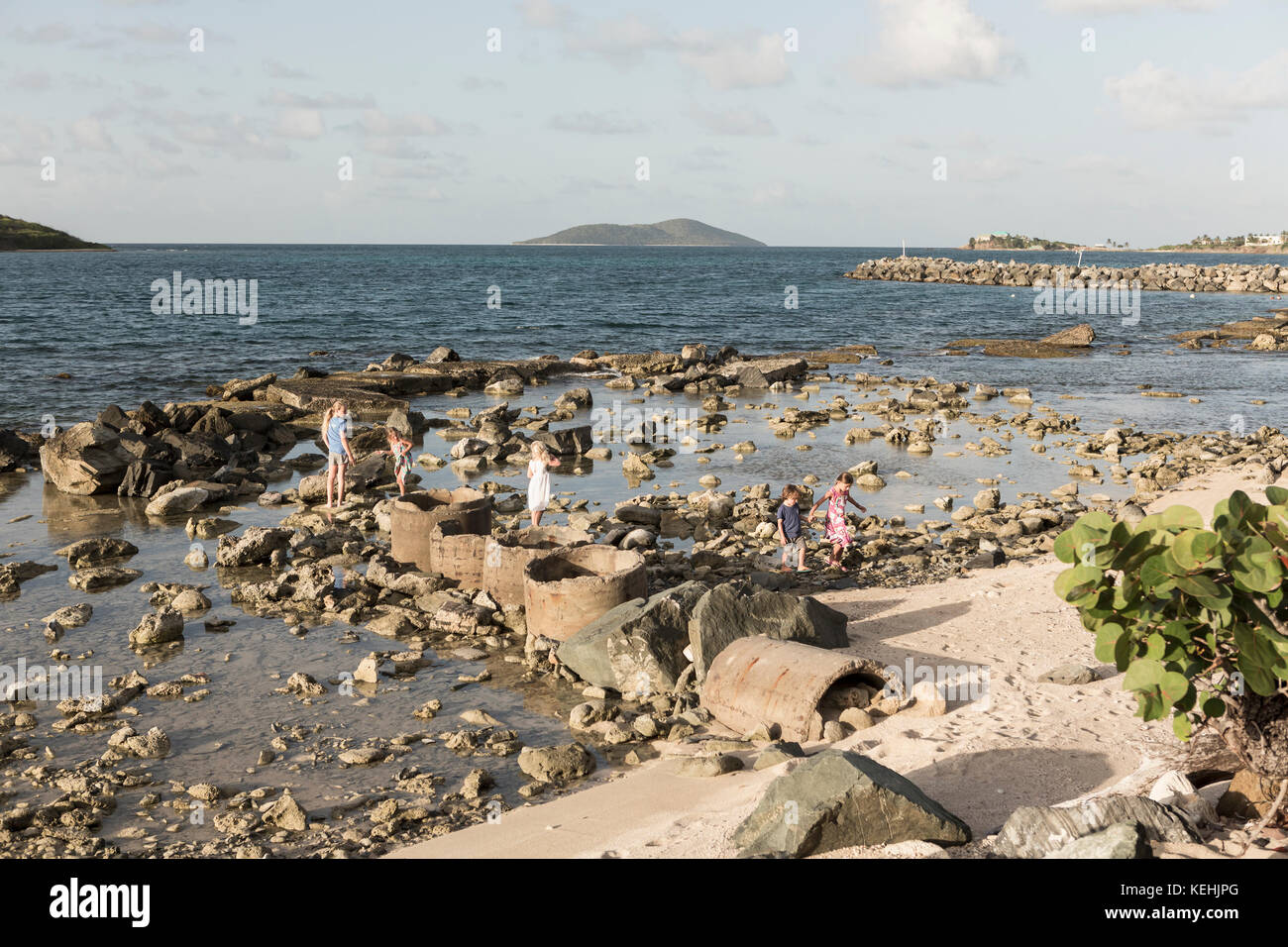 Niño caucásico y niñas caminando sobre rocas en la playa Foto de stock