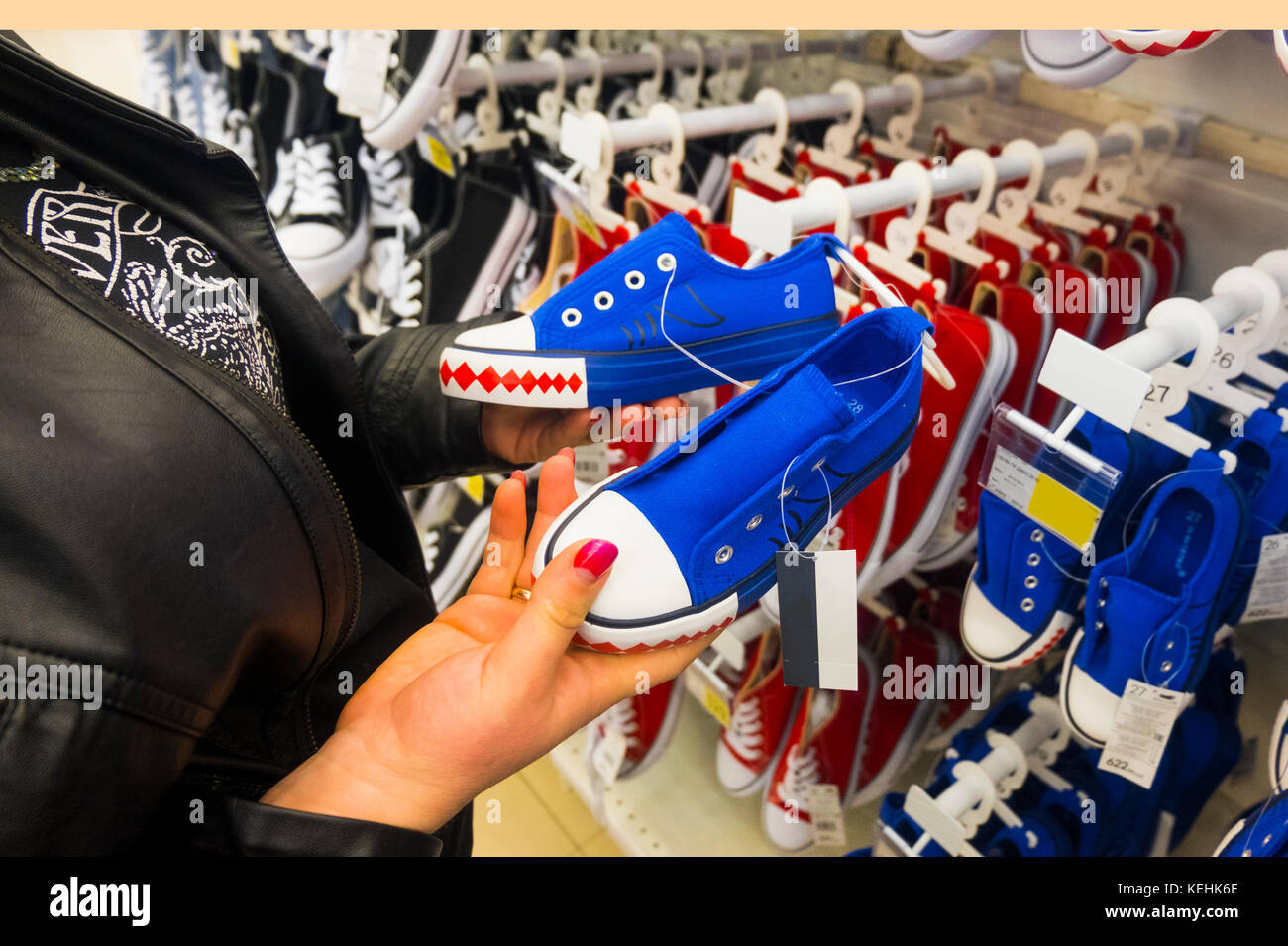 Manos de mujer caucásica celebración sneakers en la tienda Foto de stock