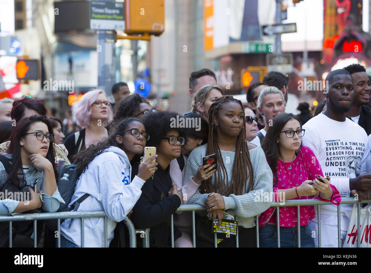 Los jóvenes y los turistas se encuentran detrás de barricadas en Times Square para echar un vistazo a los cantantes famosos que se representan en el escenario al aire libre. Ciudad de Nueva York. Foto de stock