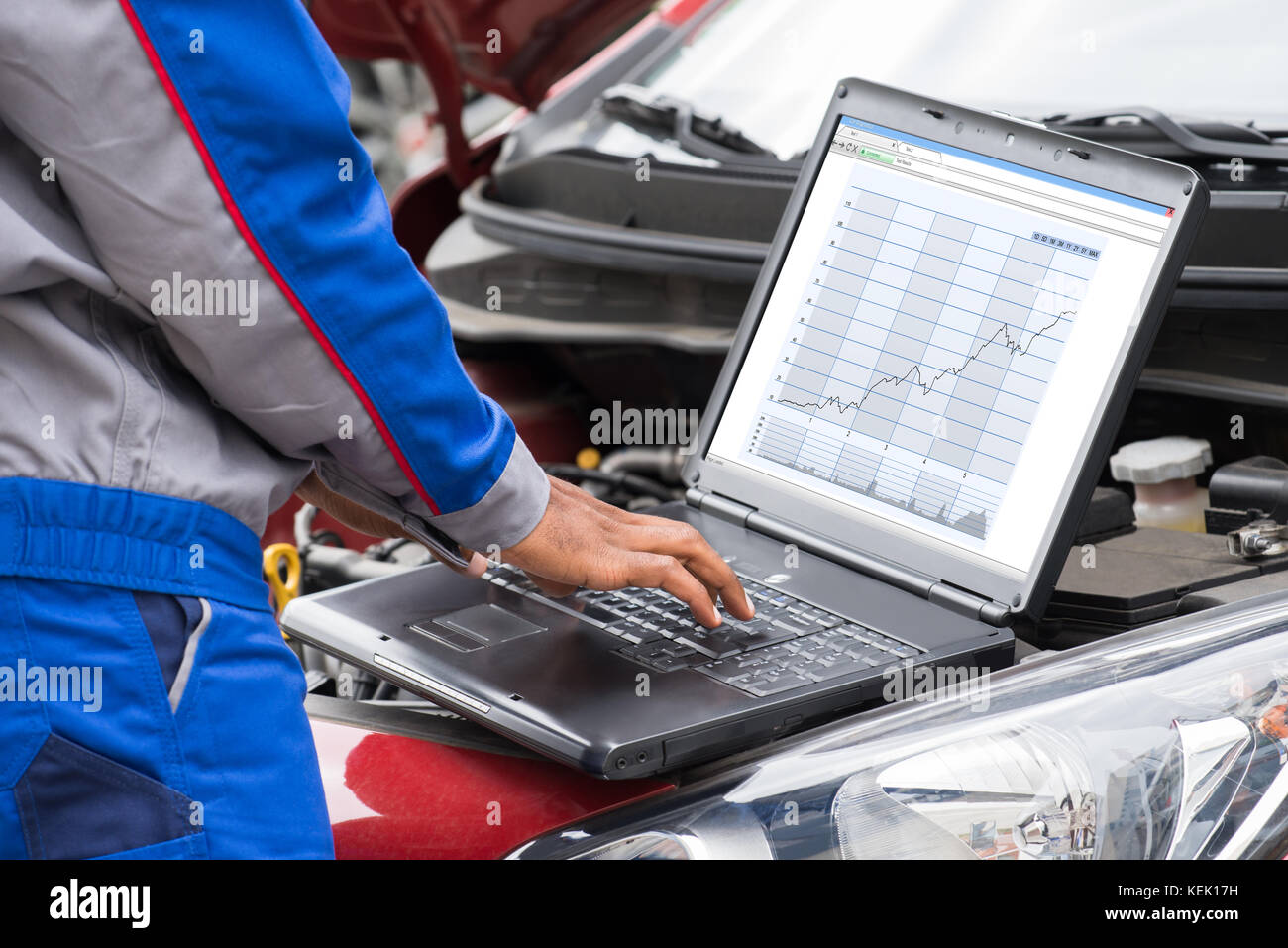 Cierre mecánico de varones con laptop para examinar el motor del coche Foto de stock
