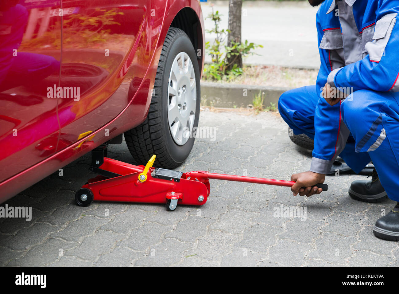 El gato hidráulico para coche se coloca debajo de auto con las manos en  guantes, primer plano Fotografía de stock - Alamy