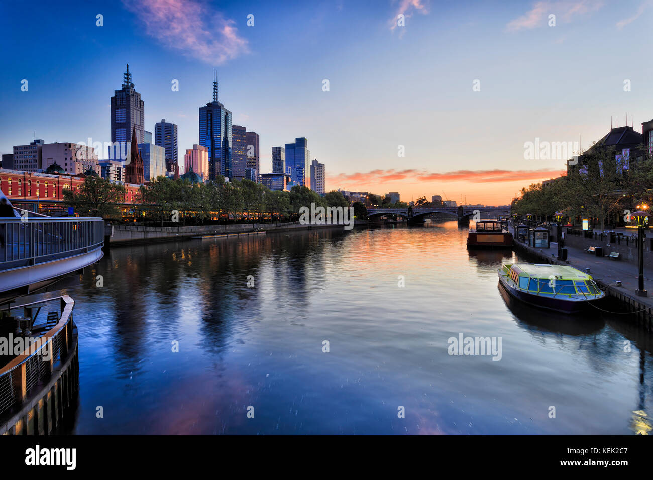Ciudad de Melbourne CBD en la zona ribereña a lo largo del río Yarra con la estación Flinders y el príncipe puente al amanecer, reflejando las luces en aguas de Yarra. Foto de stock