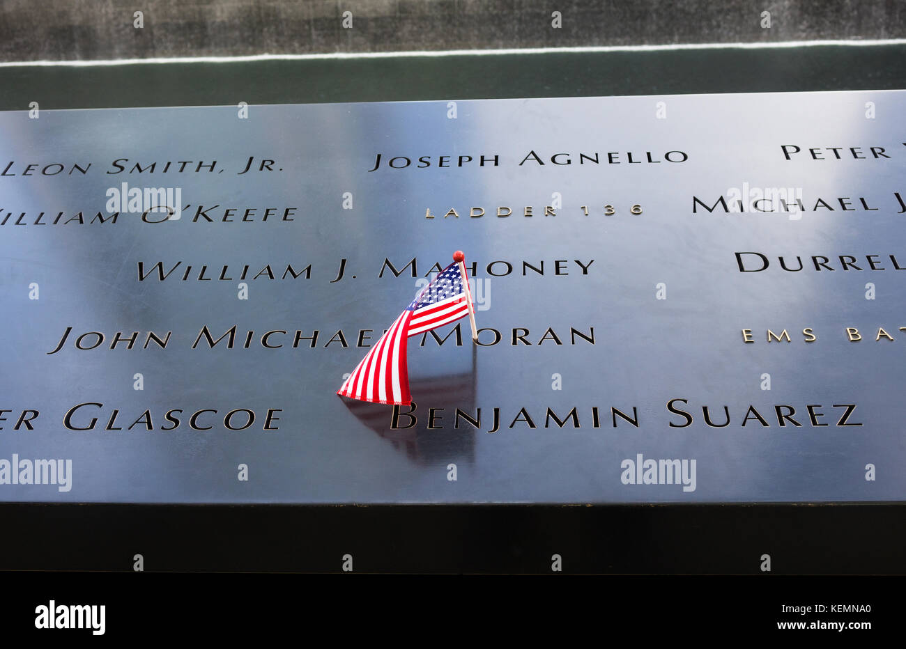 Bandera estadounidense en placa con nombres de los caídos en el North Pool Memorial en el World Trade Center en el Bajo Manhattan Foto de stock