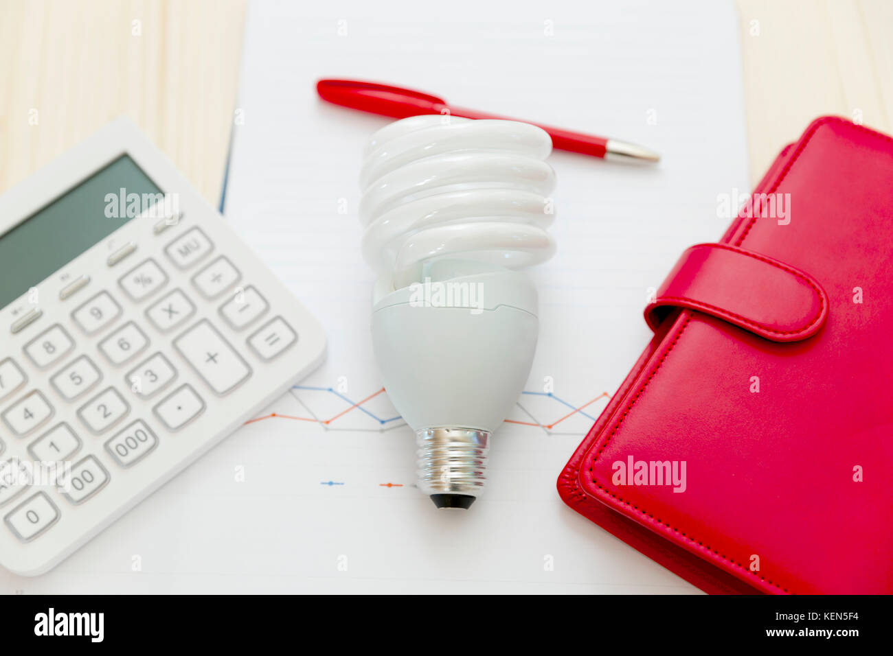 Concepto de ahorro y eficiencia energética. lampara,calculadora,lápiz,portátil  y gráfico sobre la mesa de madera Fotografía de stock - Alamy