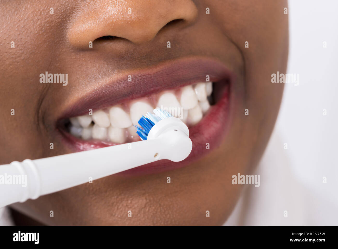Close-up de una mujer cepillarse los dientes con cepillo dental eléctrico Foto de stock