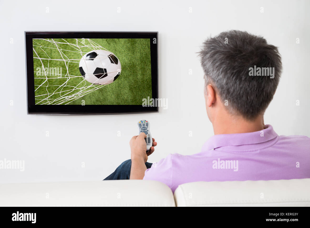 Hombre mirando el juego de fútbol en la televisión en casa Foto de stock