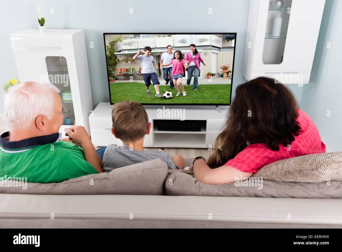 Familia viendo partido de fútbol en la televisión con niños Foto de stock