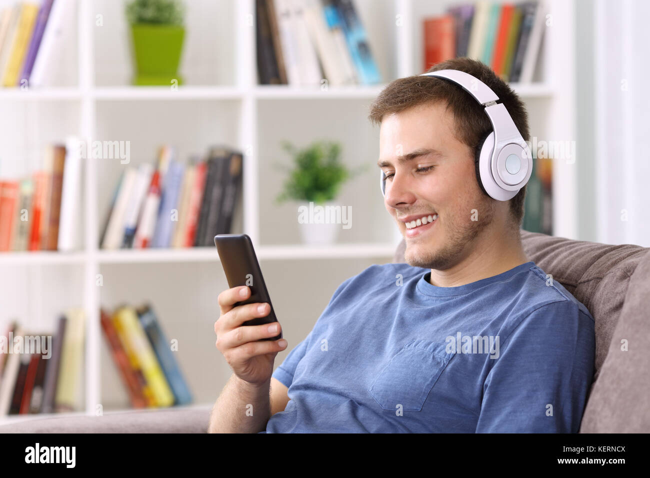 Feliz guy escuchar streaming de música sentados en un sofá en casa Foto de stock
