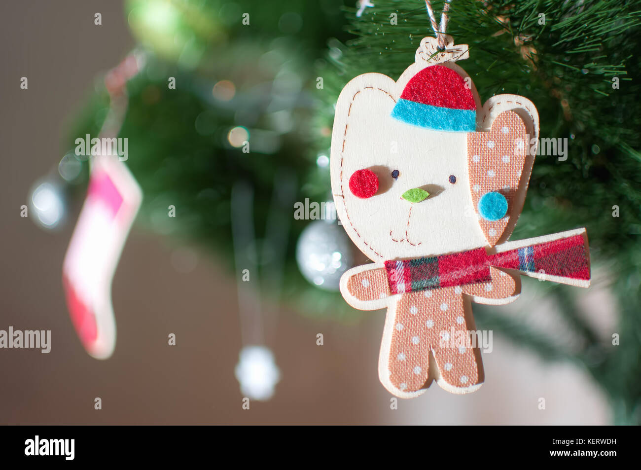 Un juguete de Navidad de madera en forma de un gato de dibujos animados  vestidos de invierno Gorra, pañuelo rojo a cuadros y el bebé romper con  lunares print está colgando de
