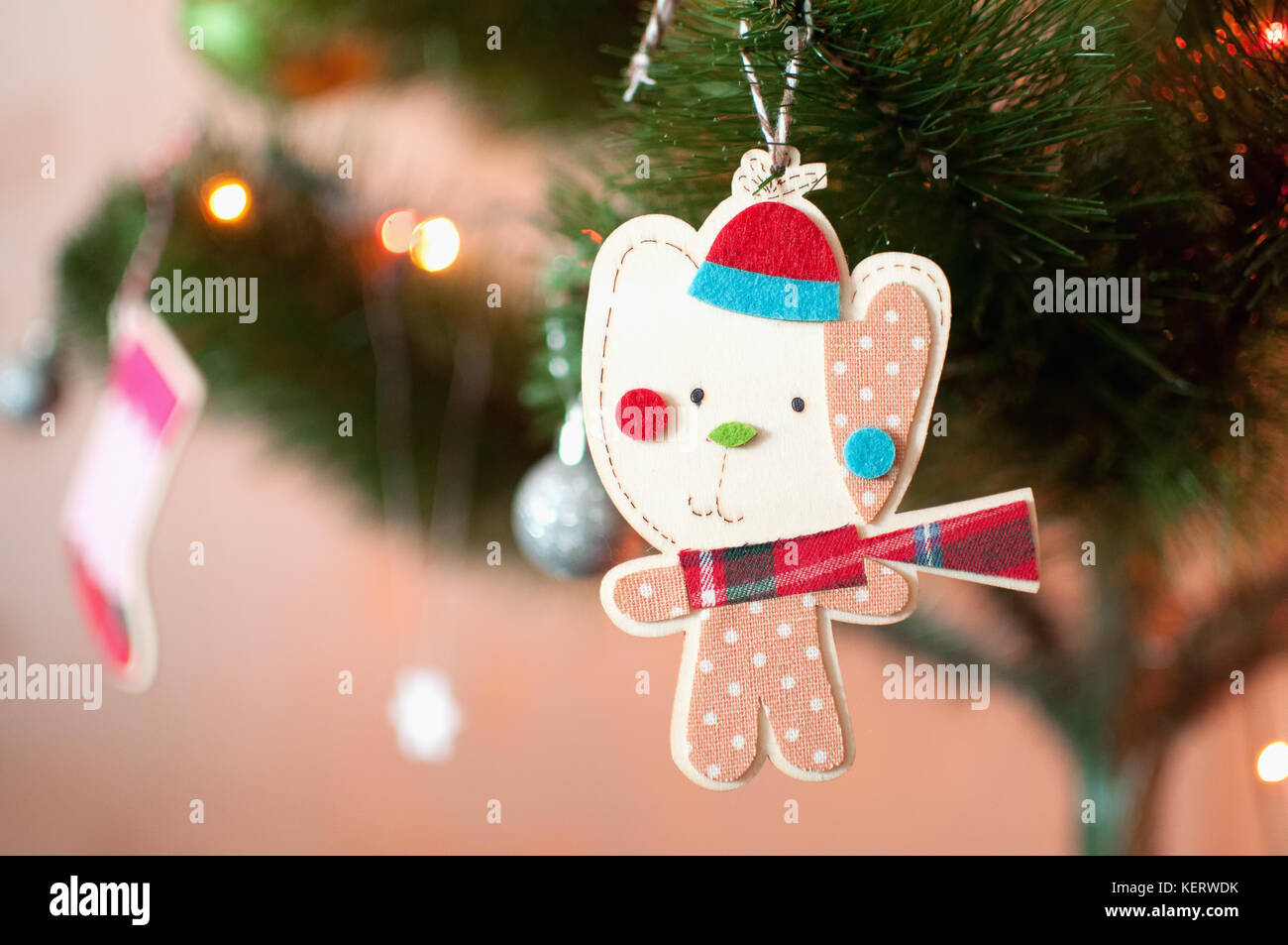 Un juguete de Navidad de madera en forma de un gato de dibujos animados  vestidos de invierno Gorra, pañuelo rojo a cuadros y el bebé romper con  lunares print está colgando de