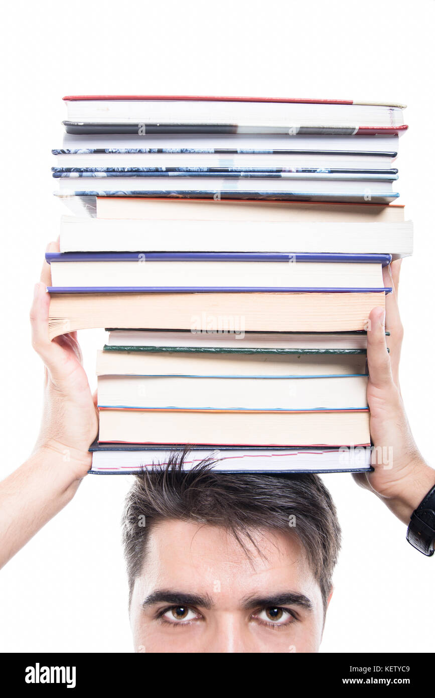 Close-up de guapo estudiante celebración pila de libros sobre su cabeza aislado sobre fondo blanco. Foto de stock