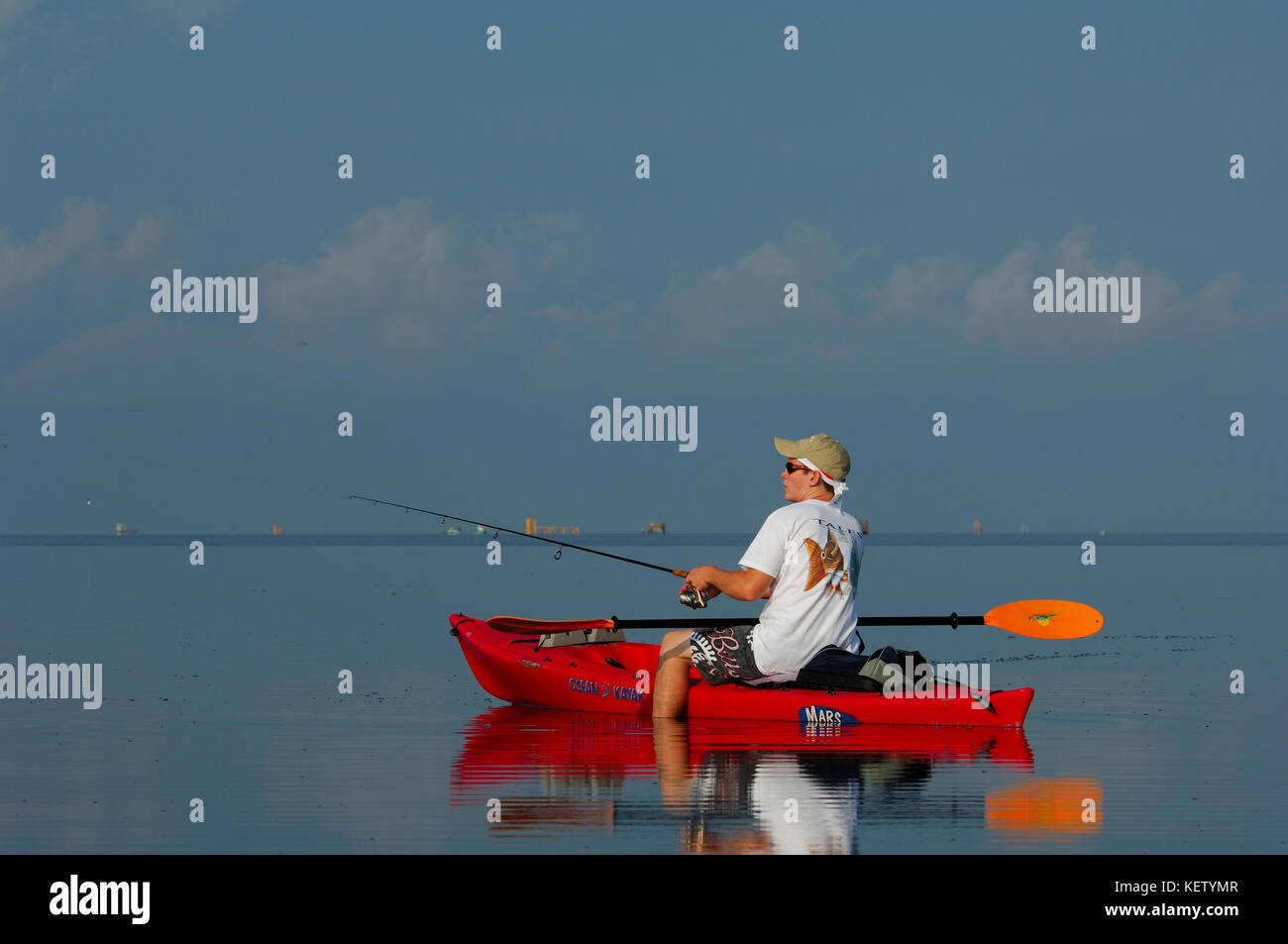 Un joven niño pesca desde un kayak de gallineta nórdica en las poco profundas aguas de pisos cerca de Port Aransas, Texas Foto de stock