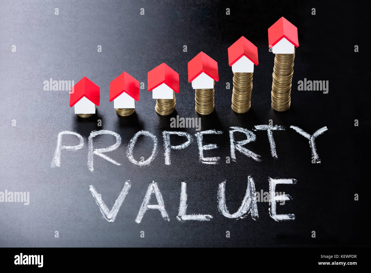 Modelos de la casa de monedas apiladas que muestra el valor de la propiedad concepto sobre blackboard Foto de stock