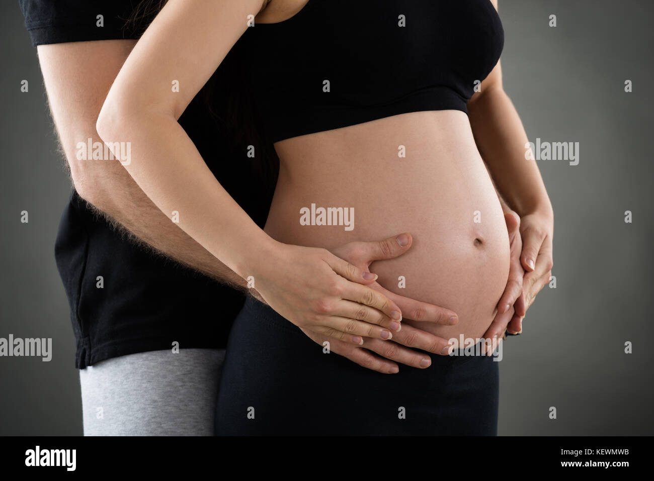 Sección intermedia del lado masculino sobre la mujer embarazada vientre Foto de stock