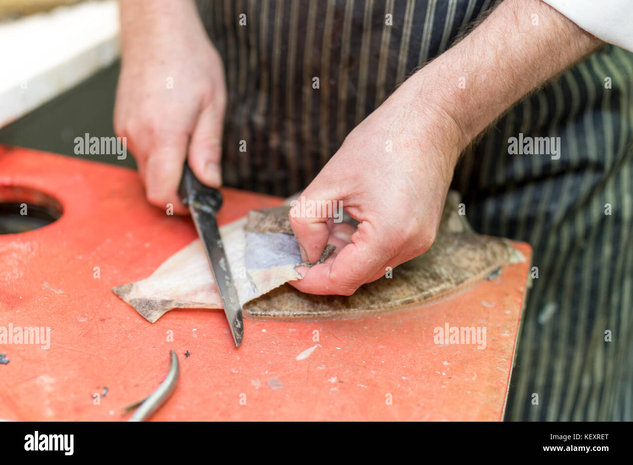 Pescado británico monger filetes de lenguado una y tira de piel lejos en un puesto en el mercado en Yorkshire, Inglaterra, Reino Unido. Foto de stock