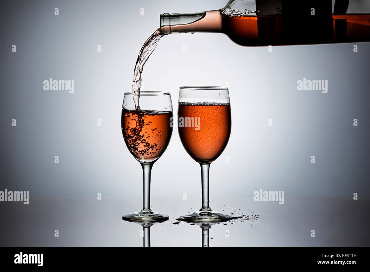 Verter rosa' vino forman una botella en las copas de vino. Foto de stock
