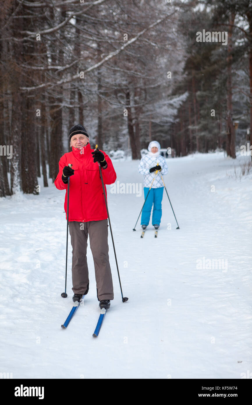 Padre e hija permanecen juntos sobre la nieve, el esquí se ejecute en bosque invernal Foto de stock