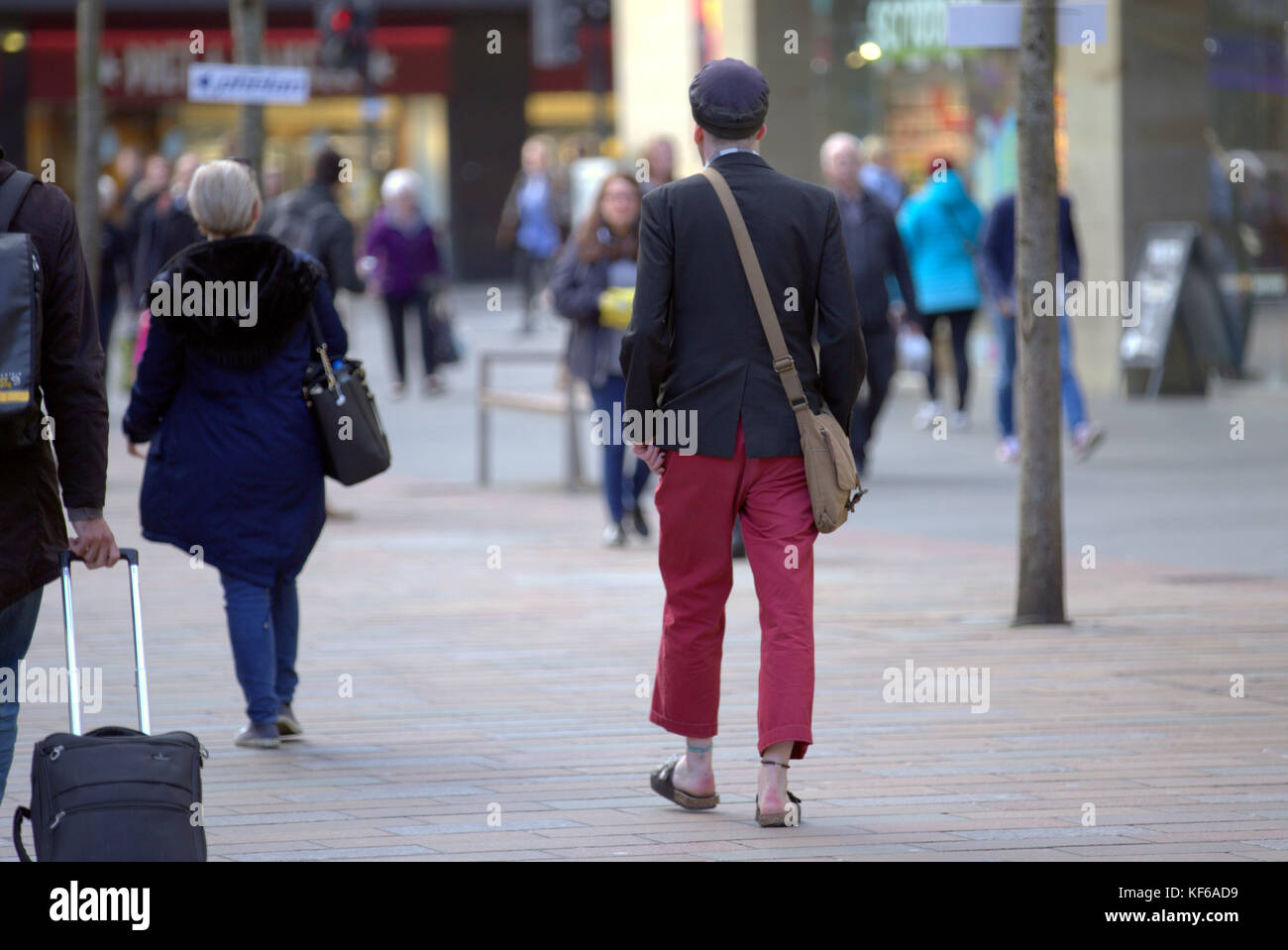 Chico de moda sin calcetines caminando visto desde detrás de la escena en la calle Acera de pavimento de Glasgow Foto de stock