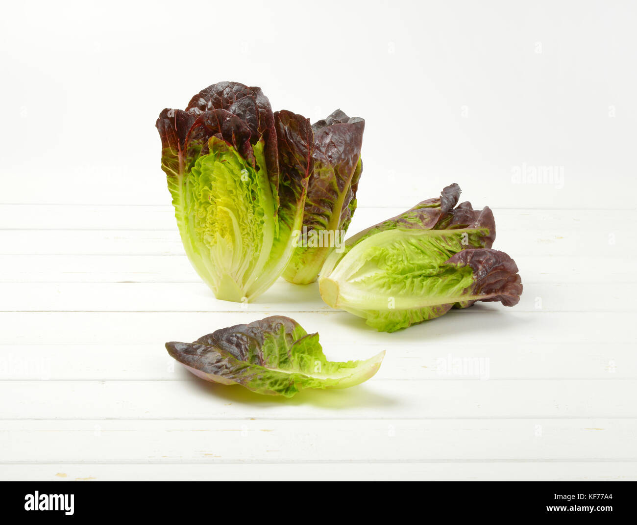 Dos y media cabeza de lechuga fresca sobre fondo blanco de madera