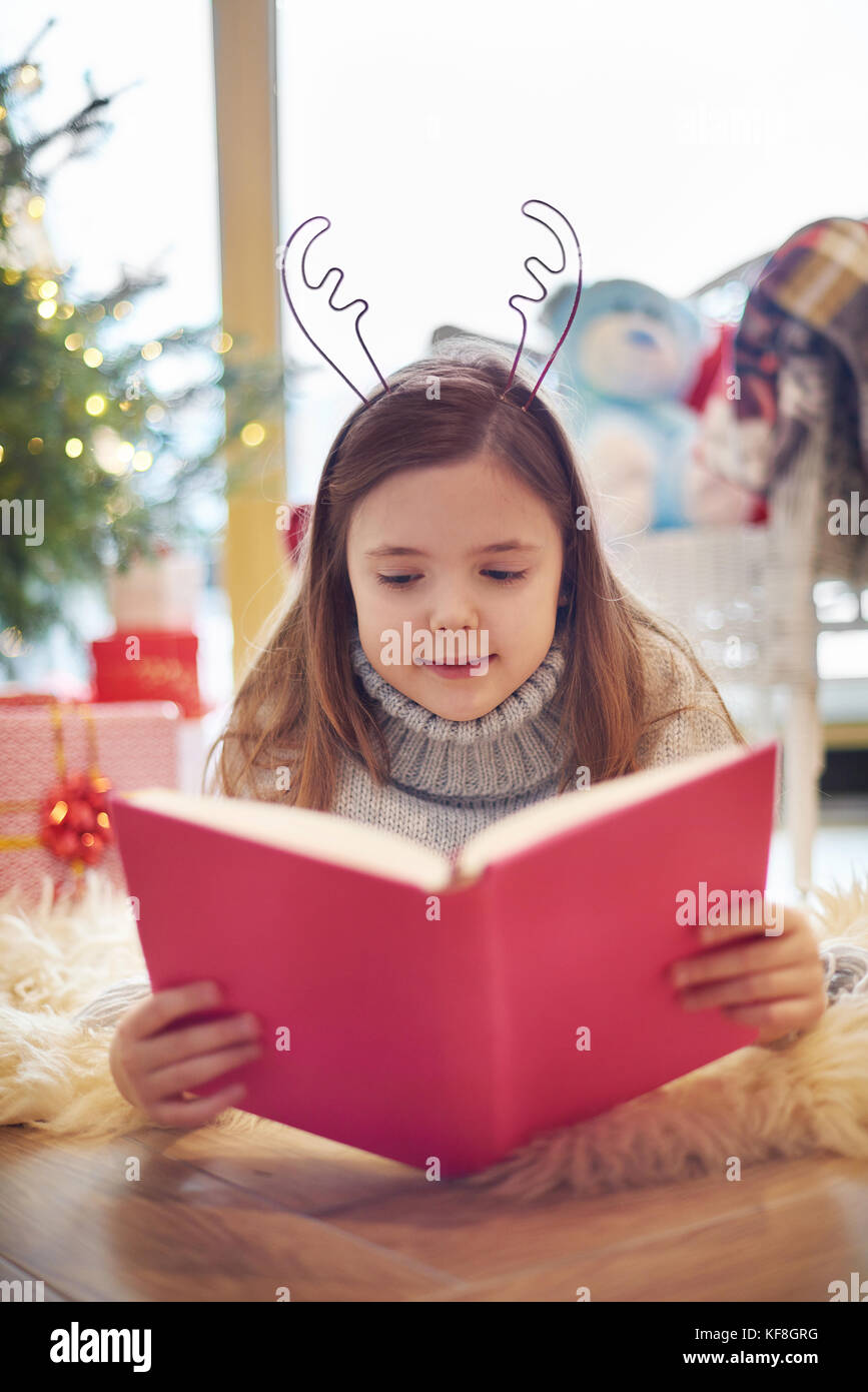 Leyendo un libro sobre vacaciones de navidad Foto de stock