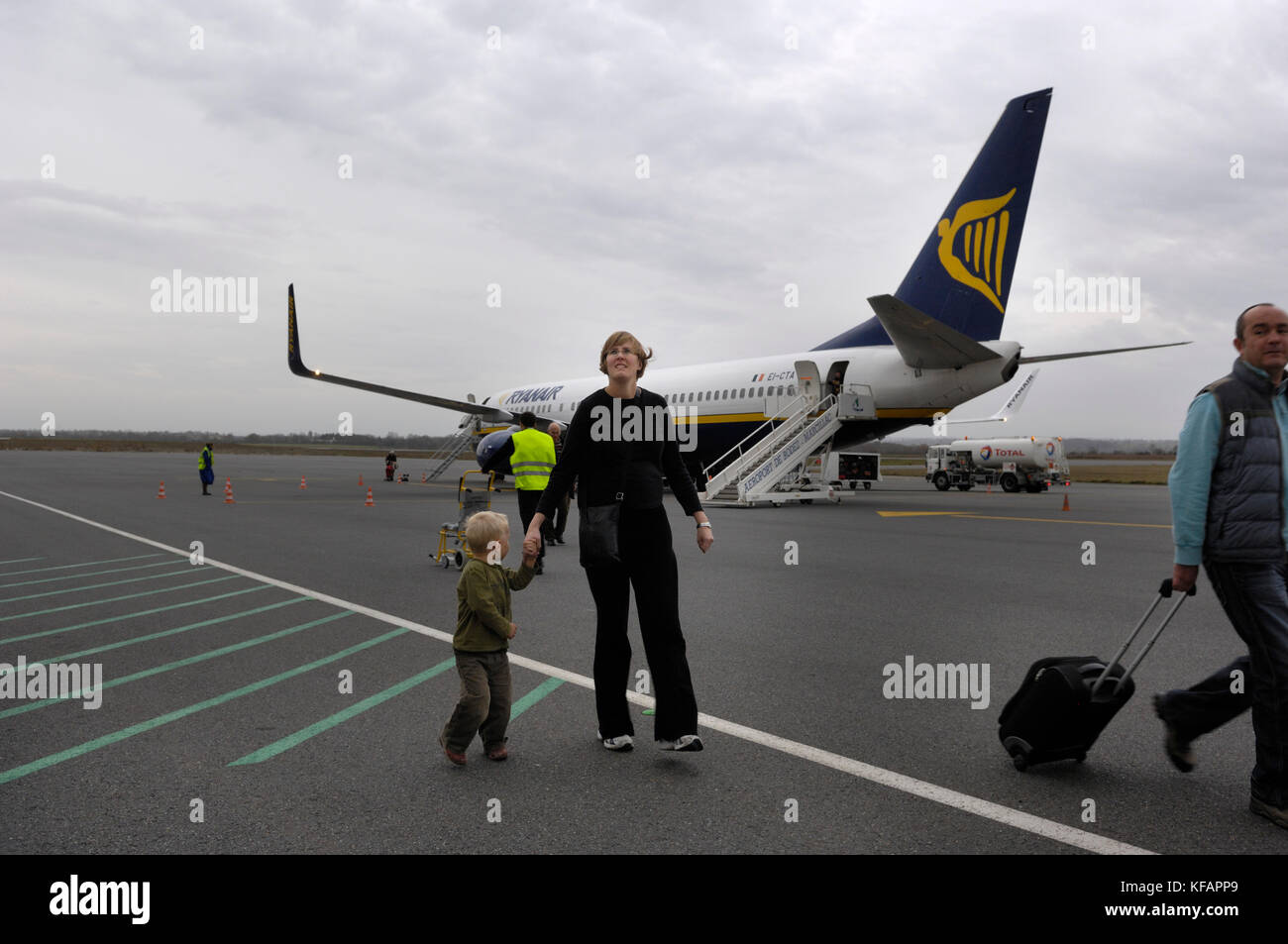 Las manos de la madre y el niño caminando con un Boeing 737-800 de Ryanair aparcado detrás Foto de stock