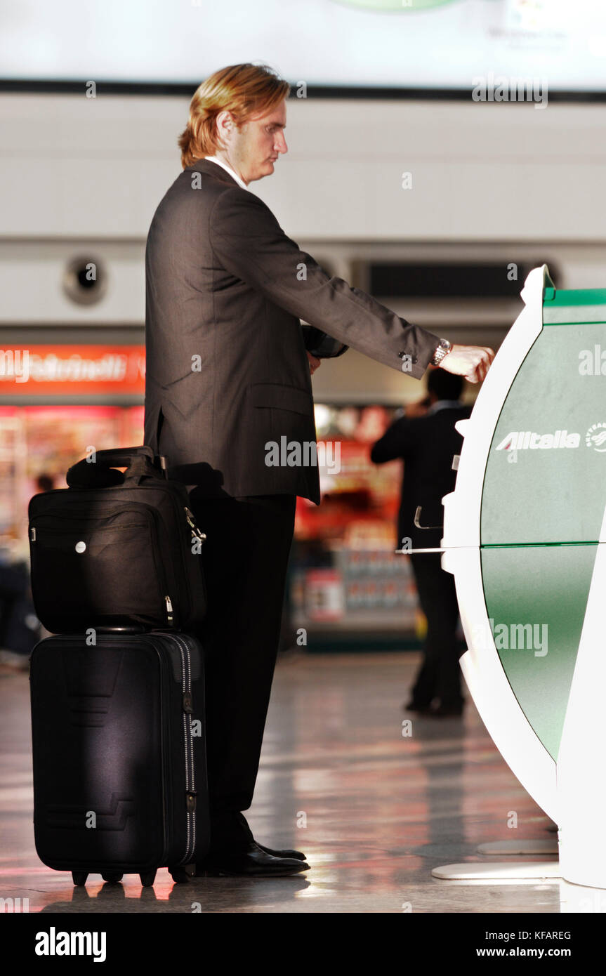 Hombre con bolsas de Alitalia utilizando una pantalla de autofacturación en  el terminal Fotografía de stock - Alamy
