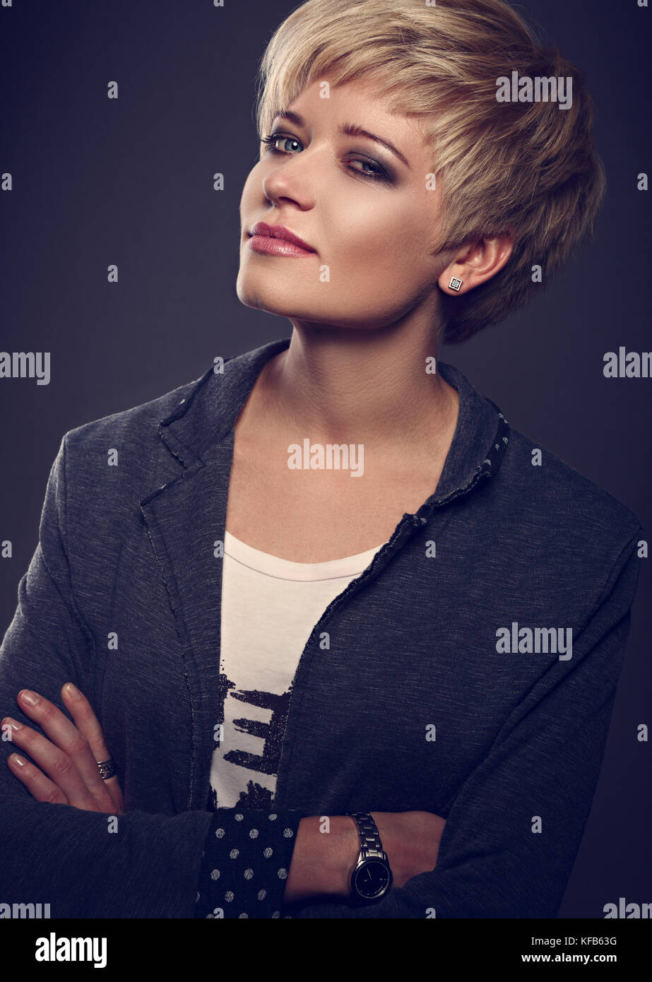 Feliz Sonriente Joven Mujer Rubia De Negocios Con Estilo De Pelo Corto Bob Busca En Gris Con Chaqueta De Moda Moda Mirar En La Mano Sobre Un Fondo Oscuro Fotografia De Stock