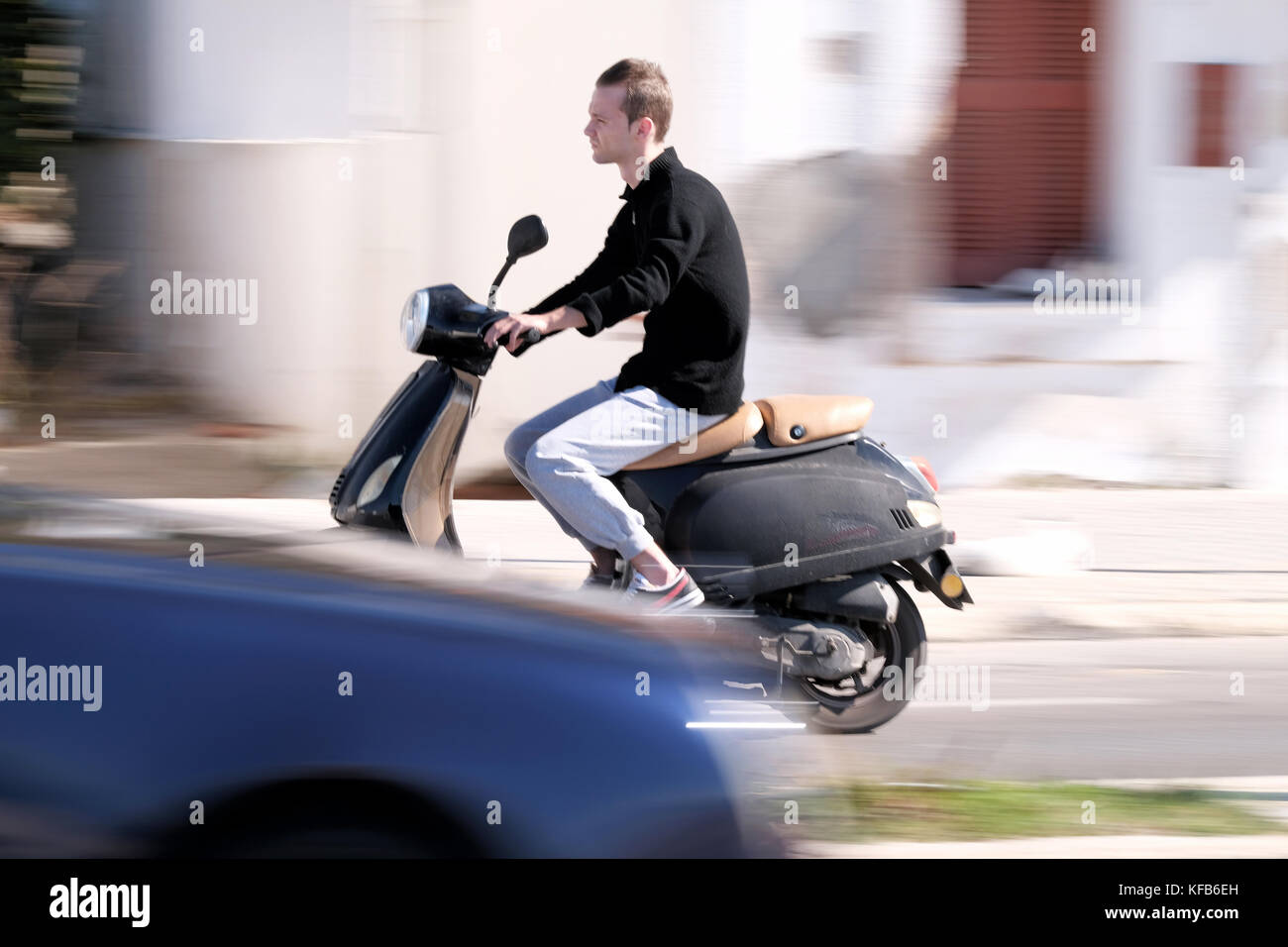 Un joven que monta un scooter a velocidad a lo largo de la carretera. El disparo se panoramaba dando una impresión de movimiento. Tomado cerca de la ciudad de Rodas, Rodas, Grecia Foto de stock