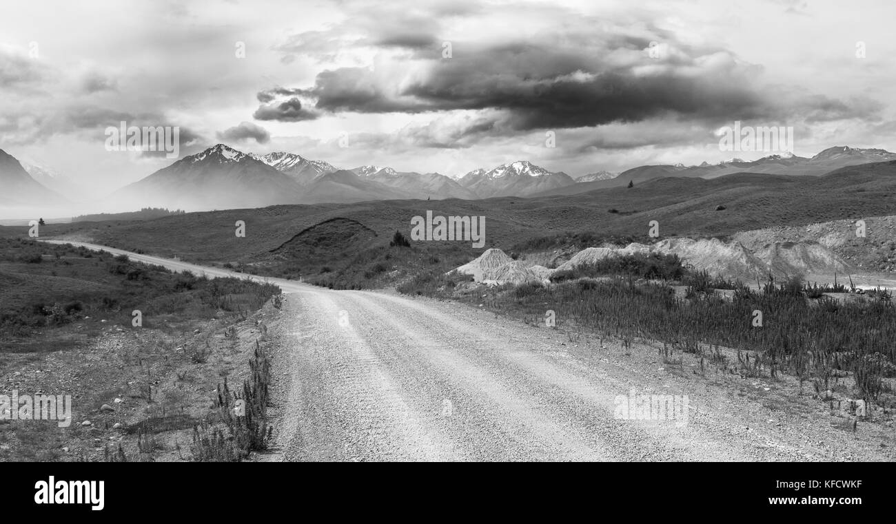 Vista del paisaje de camino de grava con montañas al fondo, cerca del Lago Tekapo, Isla del Sur, Nueva Zelanda Foto de stock