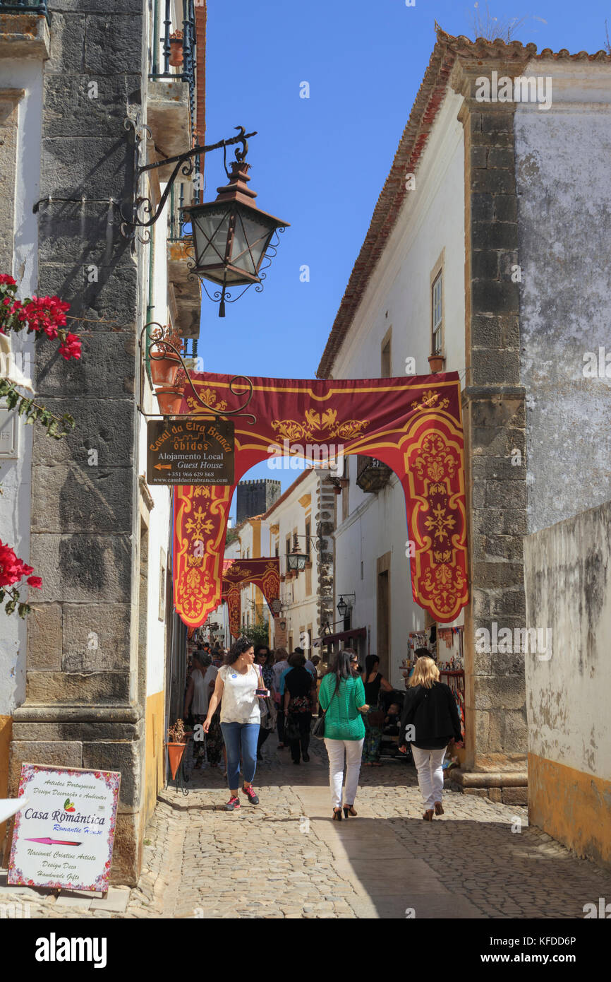 Los visitantes caminando por las estrechas calles adoquinadas de la ciudad medieval de Obidos, Portugal Foto de stock