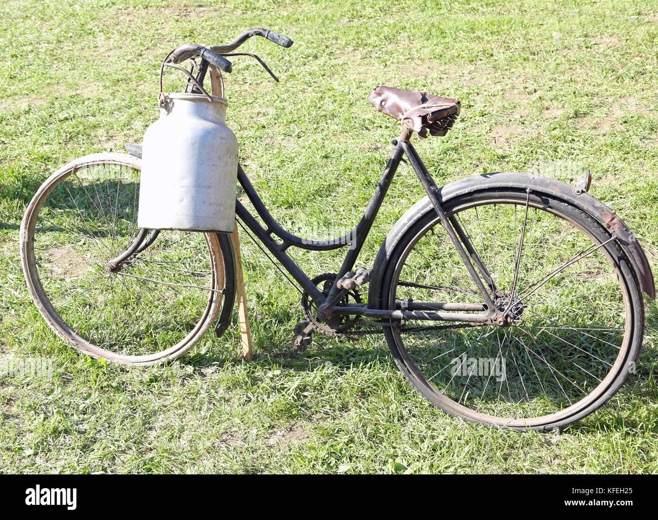 Antigua bicicleta de ordeño y aluminio lata de leche para proporcionar leche humedecido Foto de stock
