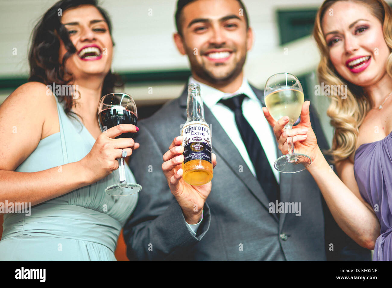 Tres amigos a tomar una copa, un hombre en traje y dos mujer sonrisa  mientras disfrutan de la bebida festiva con vino y cerveza Corona  Fotografía de stock - Alamy