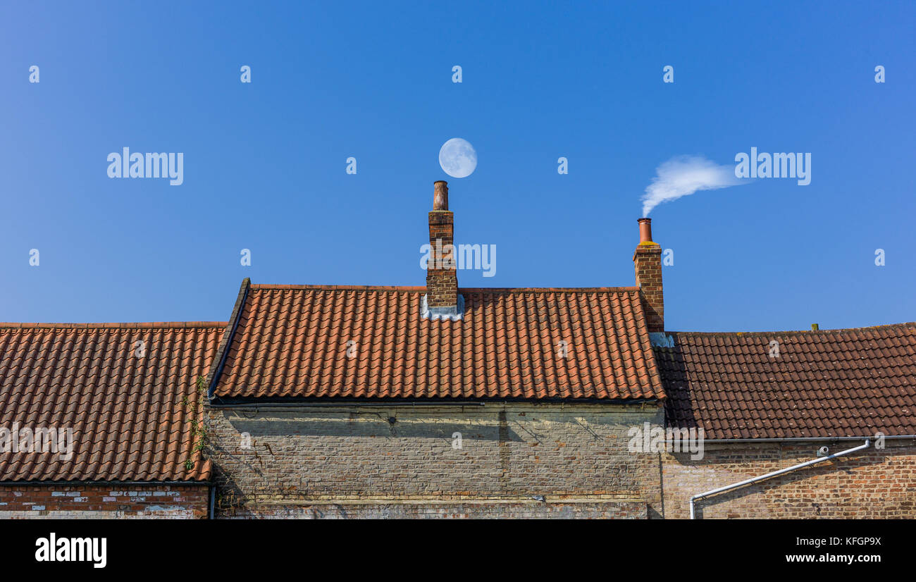 La línea del techo de la chimenea con la luna y el humo Foto de stock