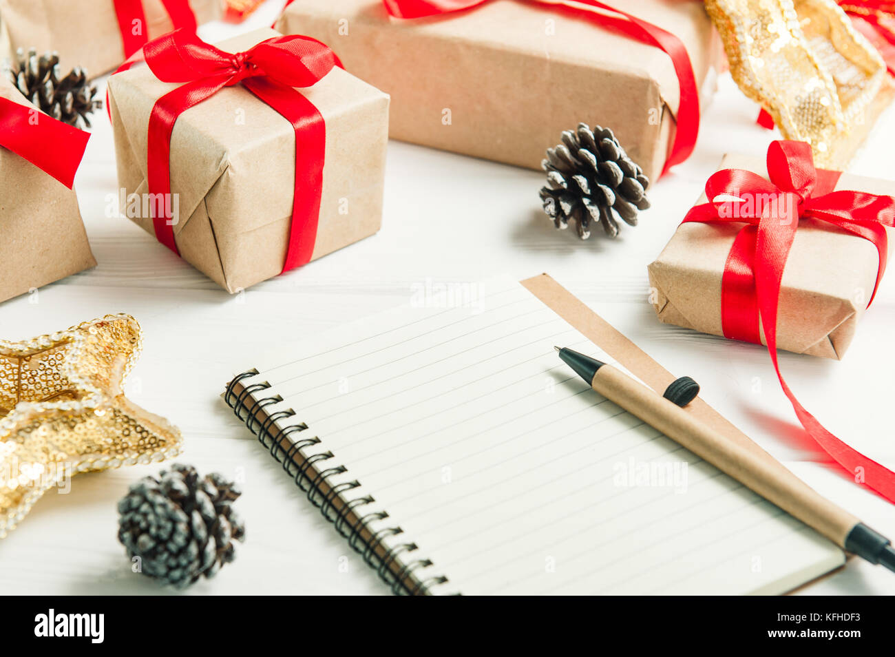 Cerrar la lista de regalos para Navidad. elaborar una lista de regalos.  presenta en papel kraft vintage fondo blanco de madera. Lápiz, cuaderno  selectiva Fotografía de stock - Alamy