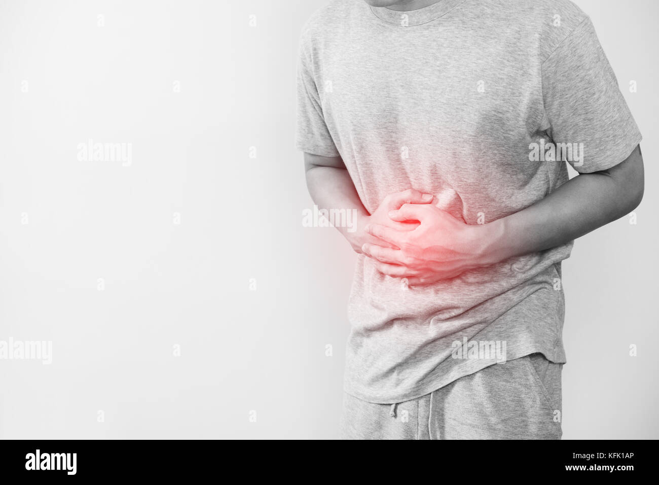 Un hombre presionando su estómago, con resaltado rojo de dolor de estómago y demás enfermedades estomacales concepto, sobre fondo blanco con espacio de copia Foto de stock