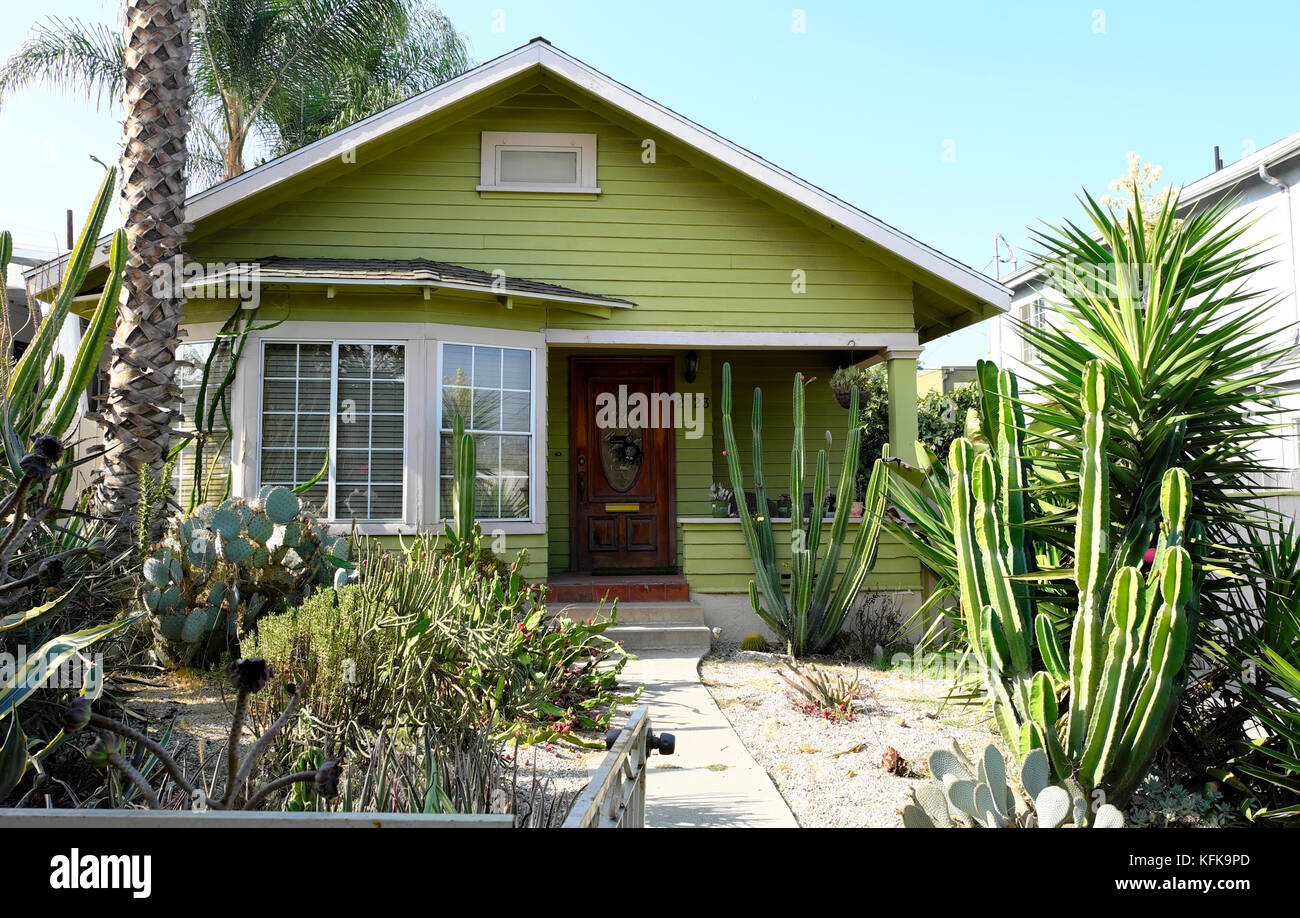 Casa y jardín delantero áridas con cactus y plantas de yuca y palmera en Frogtown del noreste de