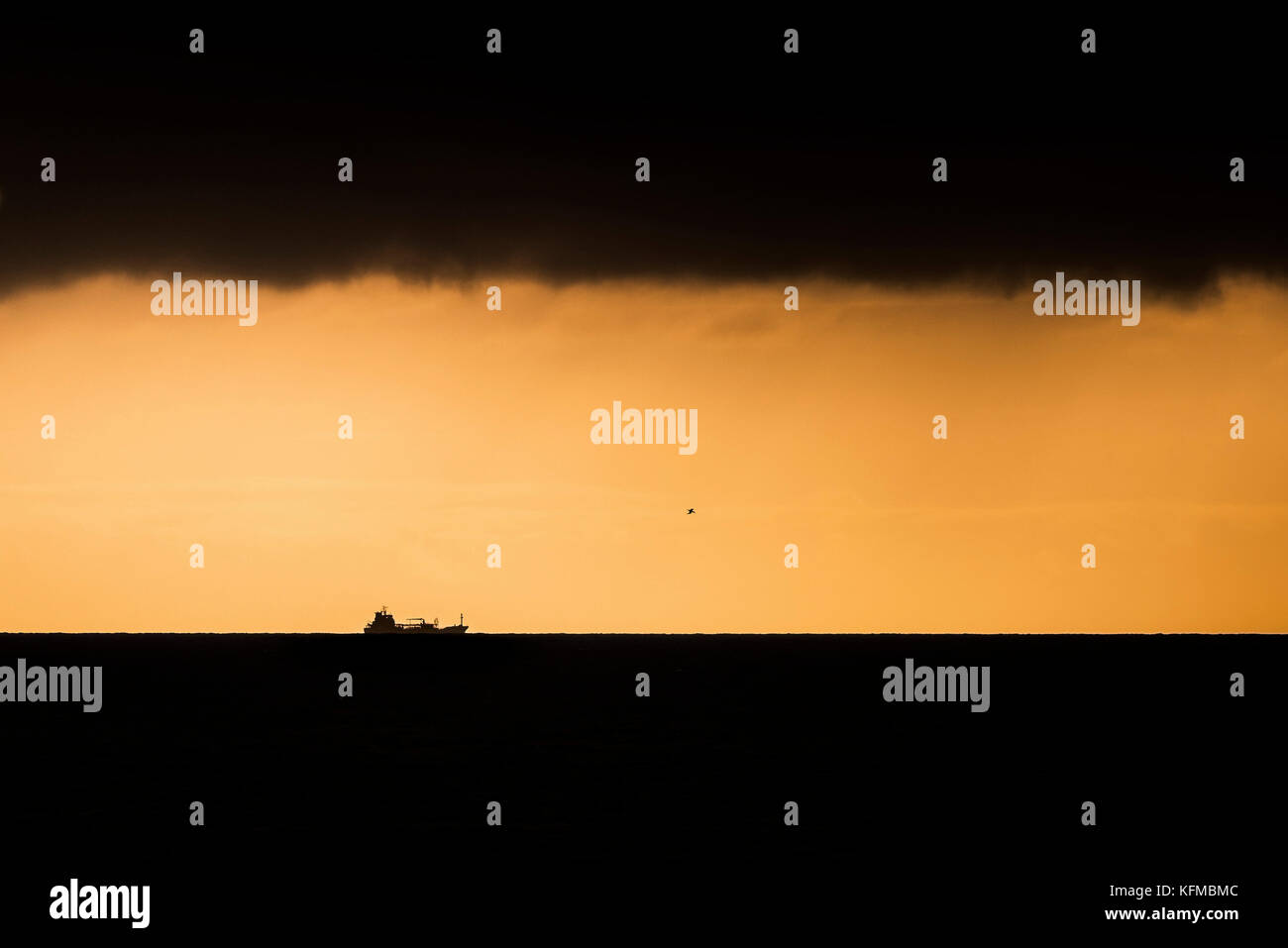 Sunset - la silueta de un barco contra una puesta del sol ardiente. Foto de stock
