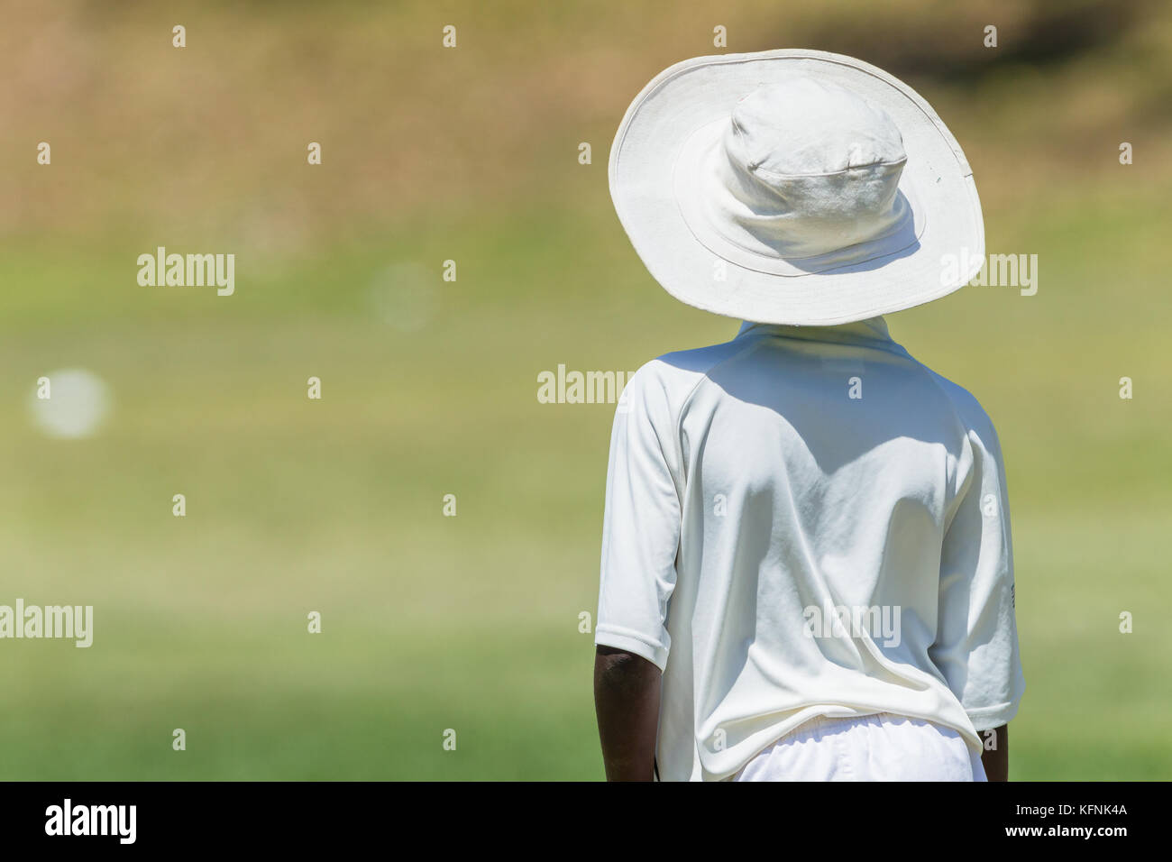 Juego de cricket jardinera jugador junior summer hat desconocidos acción abstracta. Foto de stock