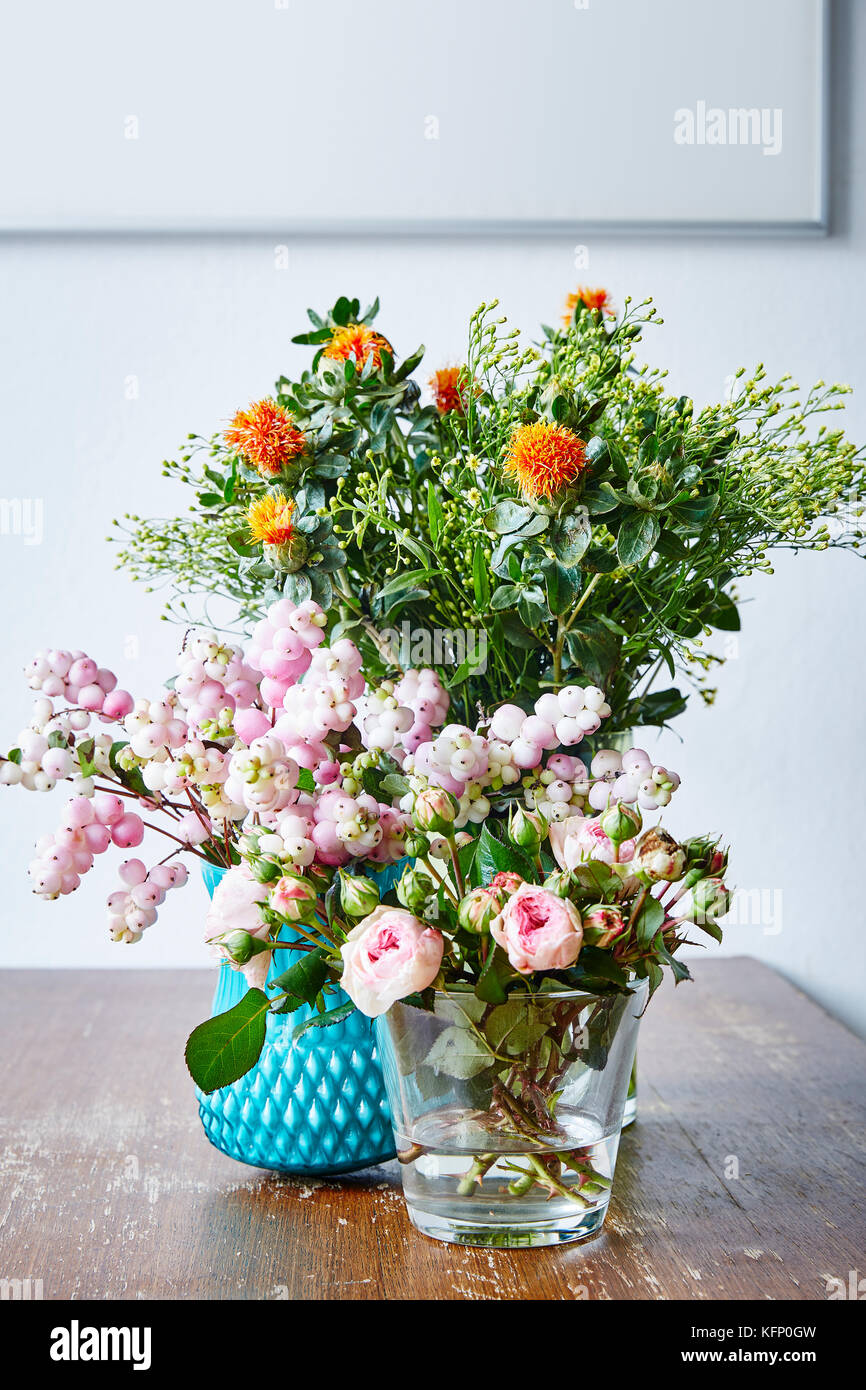 Wild Bunch de flores en jarrones diferente sobre la mesa de la cocina de madera Foto de stock