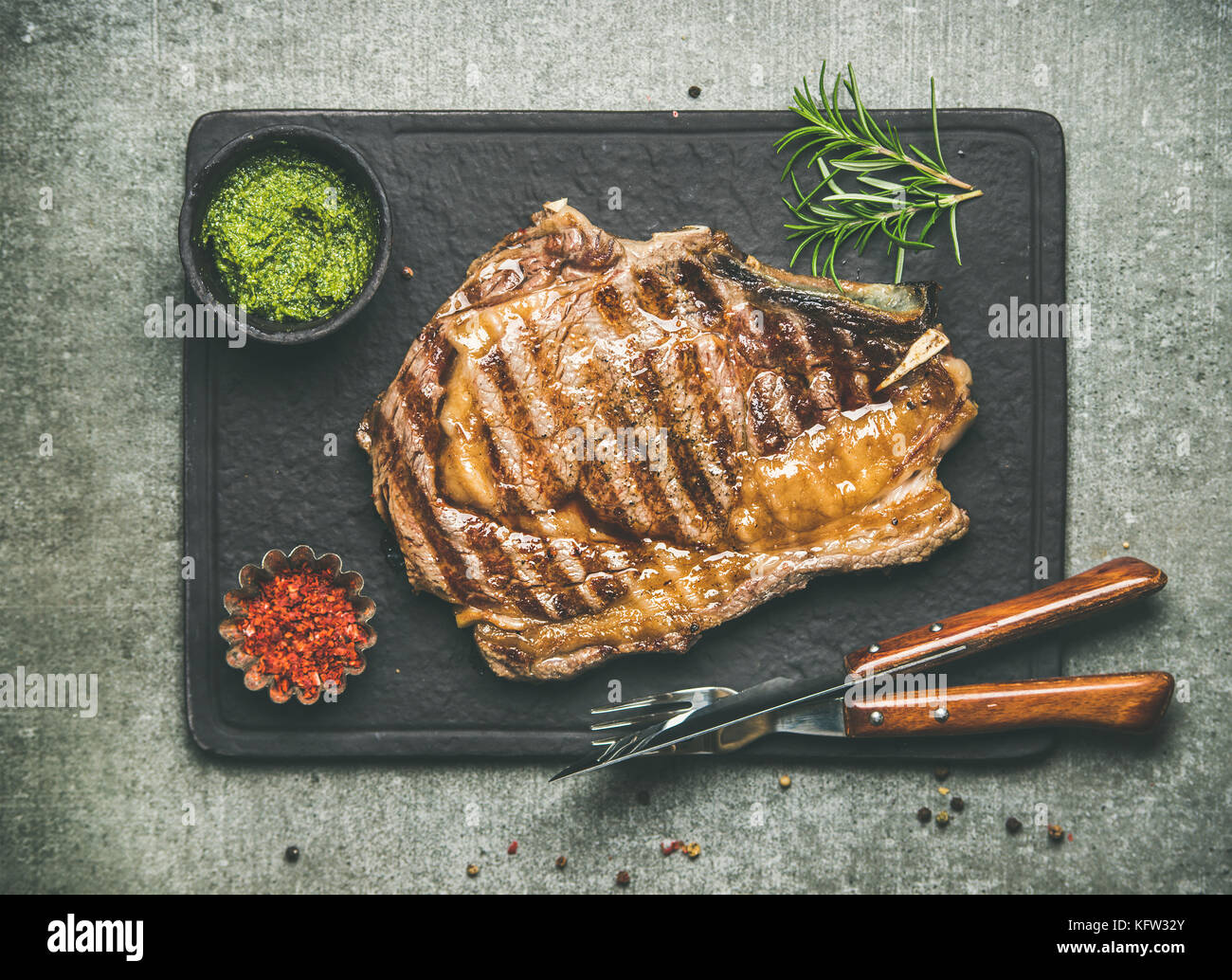 Caliente a la parrilla rib-eye steak de carne en hueso con chimichurri sauce  Fotografía de stock - Alamy