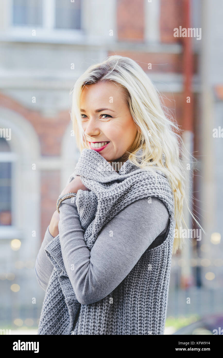 Joven elegante mujer rubia vistiendo cardigan gris caminando por la ciudad  vieja calle de moda casual, elegante Fotografía de stock - Alamy