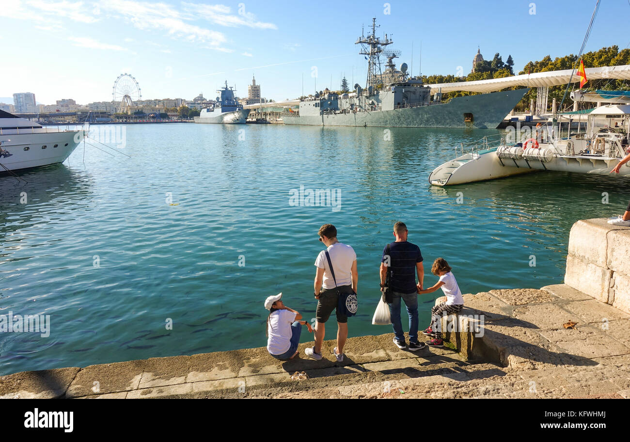 La familia de la ONU en Muelle, Muelle en el puerto de Málaga, con dos buques de guerra en el fondo, Andalucía, España Foto de stock