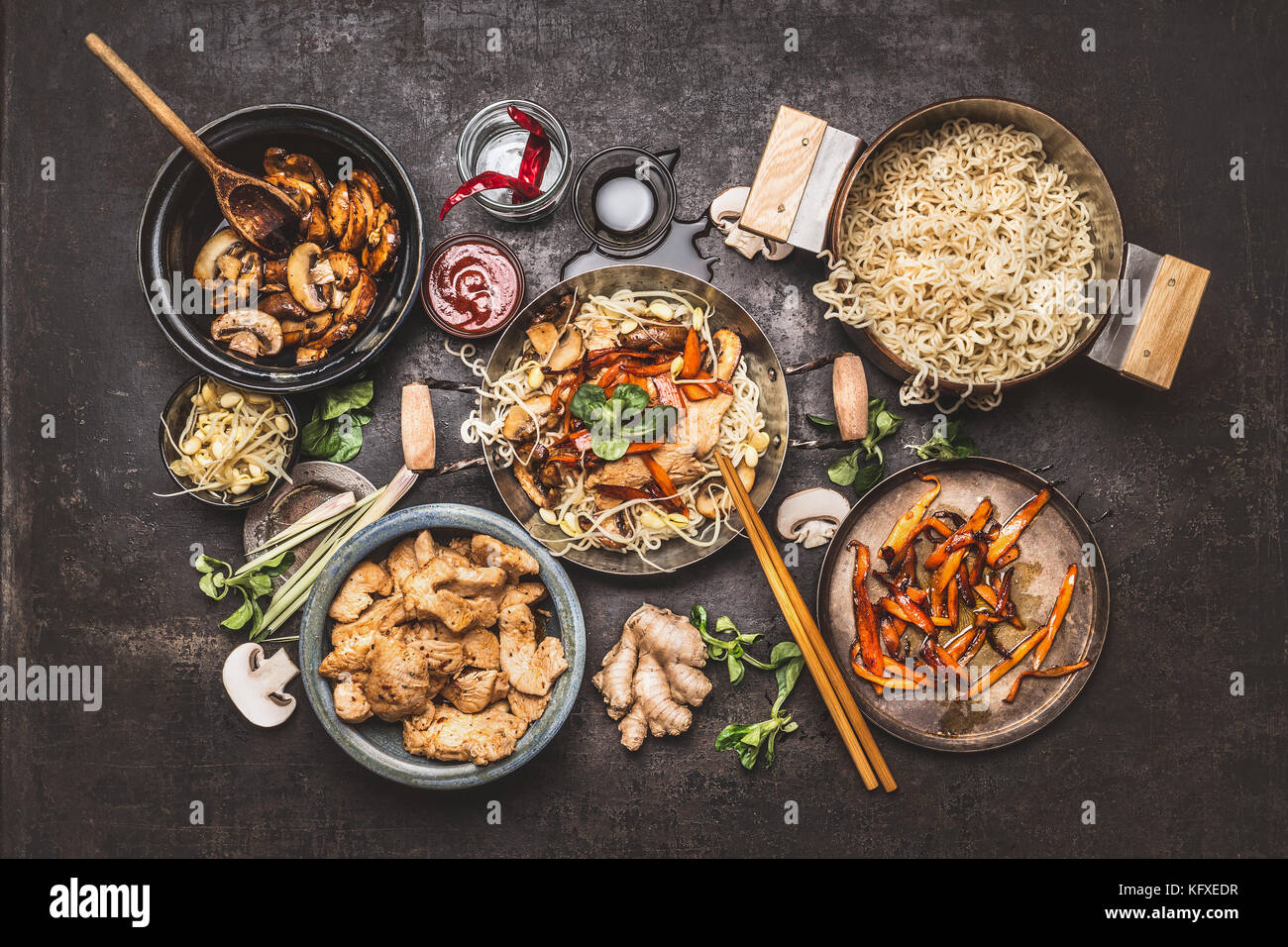 Comida asiática. wok con fideos salteados de pollo y verduras con especias  ingredientes ,salsas y palillos de oscuro fondo rústico Fotografía de stock  - Alamy